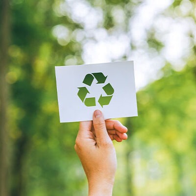 Main tenant une carte avec un symbole de recyclage dans un forêt, symbolisant le numérique responsable